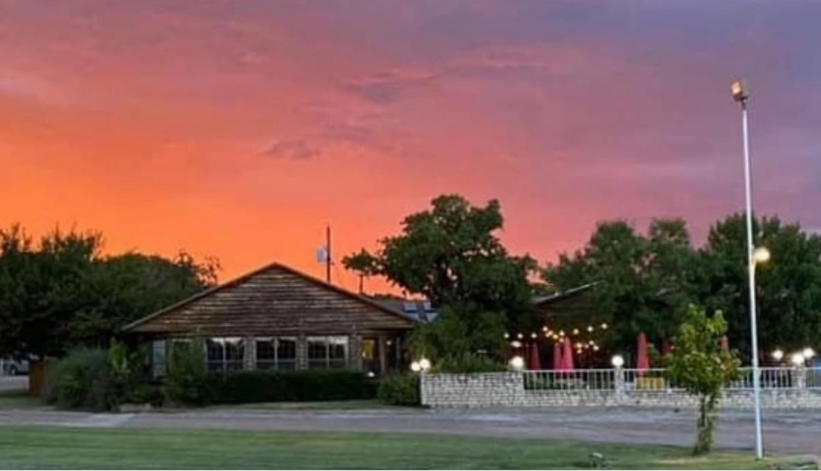 Sunset behind the Possum Hollow Lodge restaurant with patio string lights and the open lawn